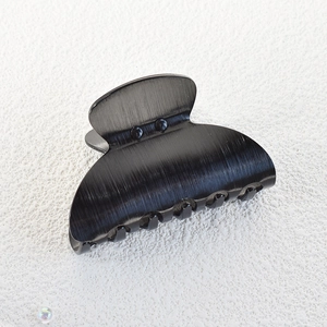 Detail view of a medium black metal hair claw clip with a stylish brushed texture finish
