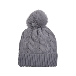 Close-up of gray chunky cable knit beanie with fluffy faux fur pom-pom for winter warmth
