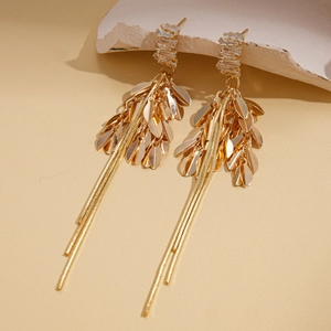 Detailed view of gold tassel earrings with zircon studs and leaf charms on stone