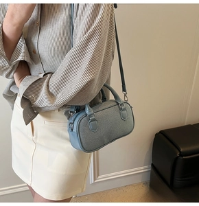 Detail of light blue crossbody Boston bag with textured fabric and leather handles