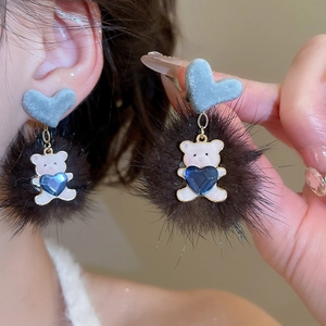 Detailed close-up of bear pendant earrings with brown fur ball and grey heart stud