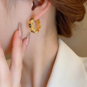 Détail de créoles vintage dorées avec étoiles en émail noir sur l'oreille du mannequin