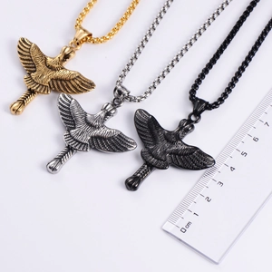 Three hawk pendants in gold, silver and black finishes shown with a 5cm scale ruler