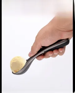 Detail of ergonomic black handle ice cream scoop serving a perfect yellow gelato ball