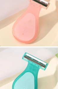 Close-up of pink and teal portable manual shavers for women with multi-layer blades