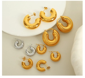 Verschiedene strukturierte hohle Creolen in Gold und Silber auf einem weißen Sockel