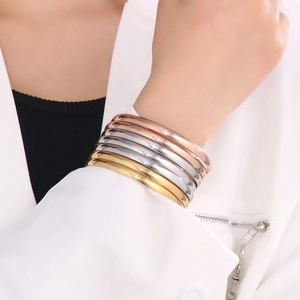 Polished titanium steel bracelets in gold, silver, and rose gold on a model wrist