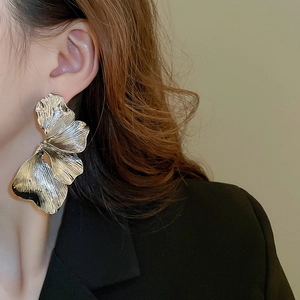 Detail of oversized silver petal earrings showing metallic texture and realistic folds