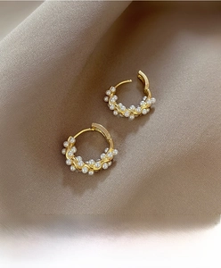 Macro shot of gold geometric earrings with pearls on brown silk satin fabric