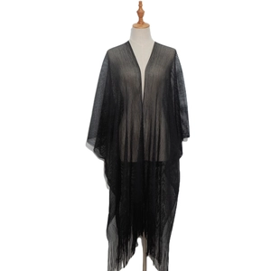 Detail of sheer black cardigan showing mesh texture and long tassel fringes on the hem