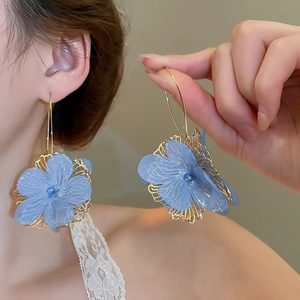 Detail of blue chiffon flower earrings with gold hooks and shimmering resin petals