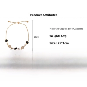 Detail of adjustable gold clover bracelet with black acetate and white zircon charms