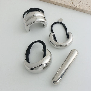 Detail of minimalist silver metal hair ties and sleek cylinder pin with a polished finish