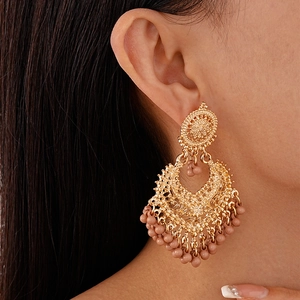 Detail of vintage bohemian tassel earrings featuring gold hollow metal and tan beads