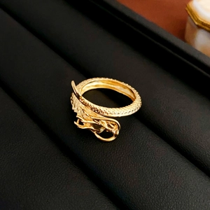 Macro detail of a golden dragon ring with intricate scale texture on a black display