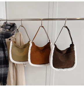 Three colors of suede bucket bags with faux shearling trim hanging on a metal rack