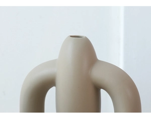 Close-up of matte beige ceramic vase with minimalist U-shaped design for modern decor