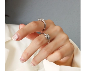 Detail shot of two silver knot-shaped stainless steel rings on a model's hand