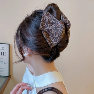 Detail of leopard print fabric bow hair claw clip styled on an elegant updo hair bun