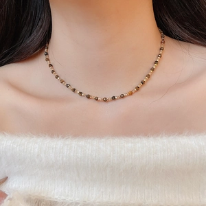 Macro detail of Tiger Eye beaded necklace on model wearing white fuzzy off-shoulder top
