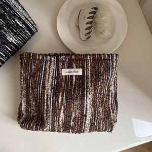 Vintage brown tweed makeup bag with simple wish label on a minimalist desk setup