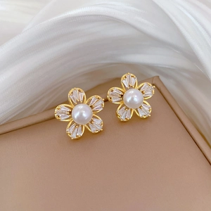 Macro shot of gold floral earrings with white pearls and sparkling cubic zirconia stones