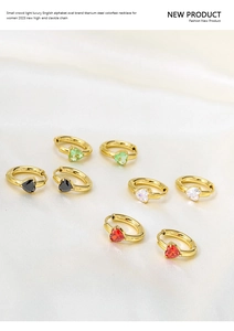 Detail of heart-shaped zircon earrings in four colors on elegant silk background