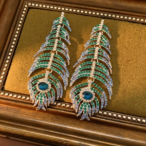 Detail of luxury peacock feather earrings featuring blue crystal accents in a vintage setting