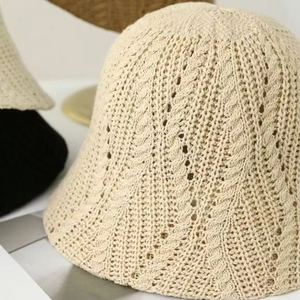 Close-up of cream knit bucket hat featuring intricate crochet twist patterns and textures