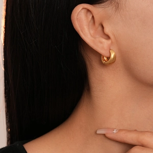 Close-up of minimalist gold plated geometric hoop earrings worn by a female model