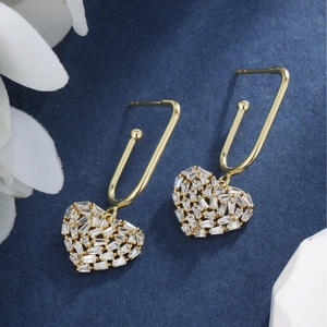 Detailed macro view of 14K gold heart earrings with baguette-cut cubic zirconia