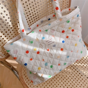 Close-up of quilted cotton tote bag with colorful dots and vintage fabric label
