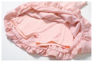 Detail view of pink athletic dress with built-in safety shorts and ruffled hemline