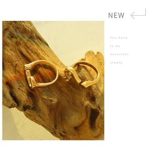 Detail of adjustable question mark gold ring on textured weathered wood background