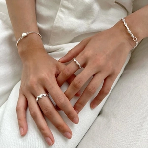 Minimalist silver jewelry set featuring heart rings and bracelets on a knit background