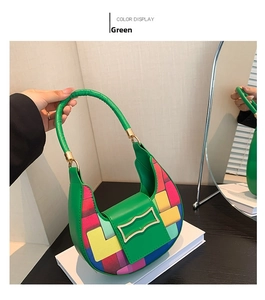Close-up of green crescent bag with colorful artistic patchwork and golden metal snap