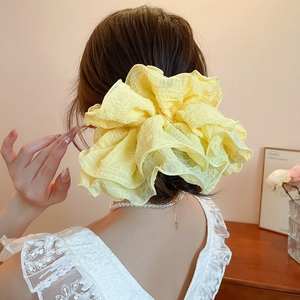 Detail showing high-volume yellow pleated fabric hair scrunchie on model hair