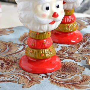 Hand-painted Santa Claus ceramic dessert cup in red and gold on blue table runner