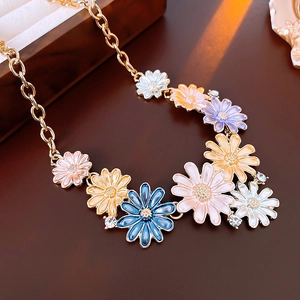 Macro detail of colorful enamel daisy flowers on golden necklace with sparkling crystals