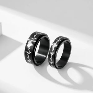 Détail de bagues rotatives noires pour couples avec motifs de rythme cardiaque argentés