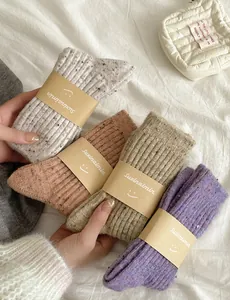 Detail of four-color thick wool knit socks with vintage flecked texture and paper packaging