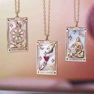 Three gold-plated tarot card necklaces featuring The Wheel, Lovers, and Strength designs