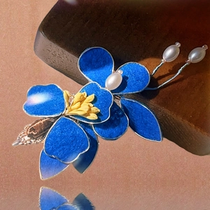 Dettaglio del fermaglio a fiore in smalto blu con pistillo giallo e perle