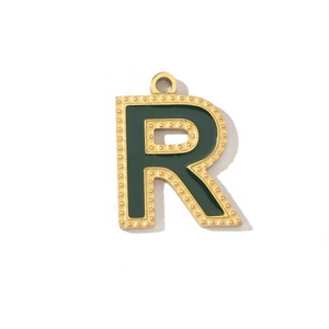 Macro shot of letter R gold pendant with dark green enamel and beaded edge detail