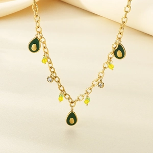 Golden chain necklace with green enamel avocado pendants and sparkling beads on beige cloth