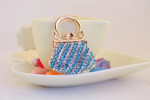 Detail of gold rhinestone bag charm with blue and clear crystals on heart saucer