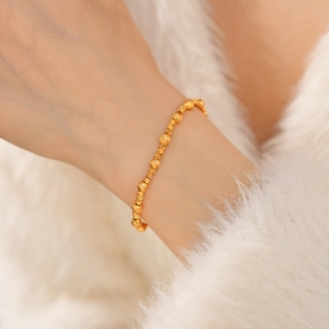 Detail of 24k gold-plated beaded bracelet with alternating smooth and engraved gold beads
