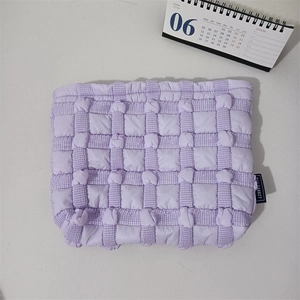 Detail of light purple bubble quilted canvas makeup bag with woven brand label tag