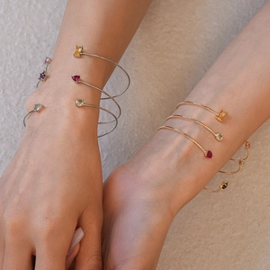 Détail de bracelets spirales en zircon superposés en or et argent sur modèle