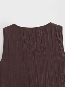 Gros plan sur la texture plissée marron foncé et les détails du col sans manches